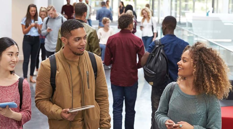 College students walk and talk in a crowded modern building