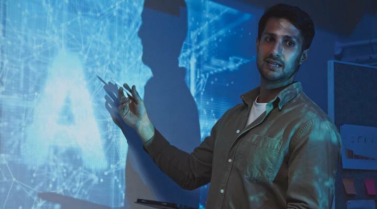 A man stands in front of an abstract representation of artificial intelligence