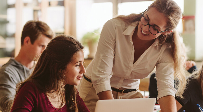 An instructor works with students in a classroom setting