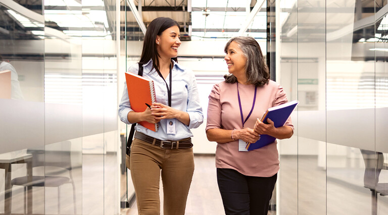 Two women chat about CIEM in an open hallway