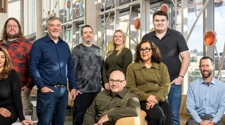 A team of IT employees at the Universities of Wisconsin pose for a photo.