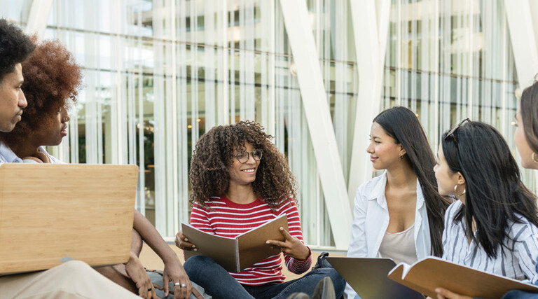 A group of students chat outside on a college campus