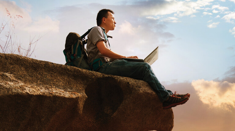 Student using laptop in the wilderness