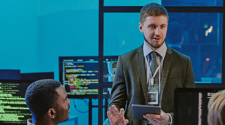 exec talking to 2 people in front of computer screens