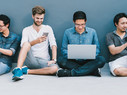 four men using smartphone, laptop computer, digital tablet together with copy space on blue wall