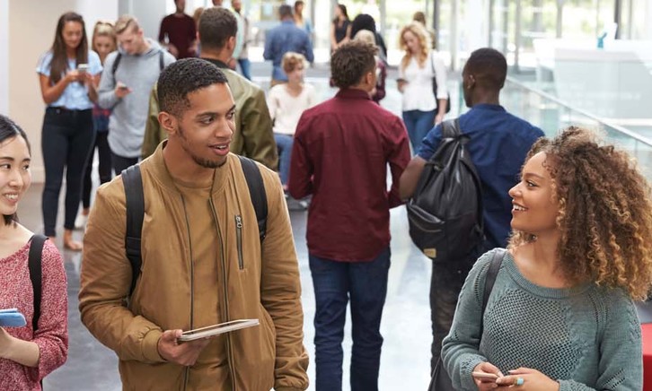 College students walk and talk in a crowded modern building