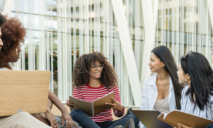 A group of students chat outside on a college campus