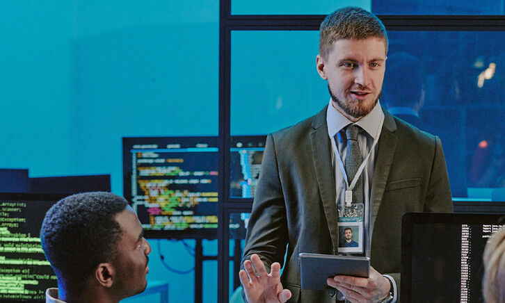 exec talking to 2 people in front of computer screens