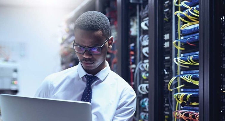 An IT worker on his laptop inside a data center
