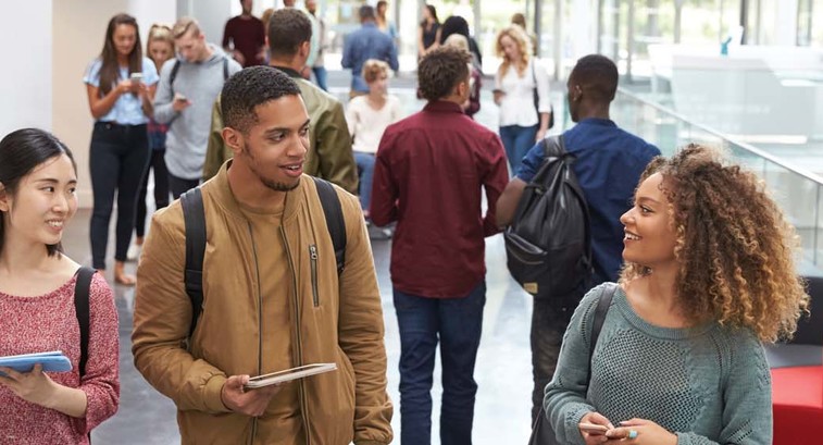 College students walk and talk in a crowded modern building
