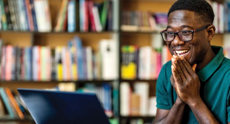 A young man reacts excitedly to a message on his laptop
