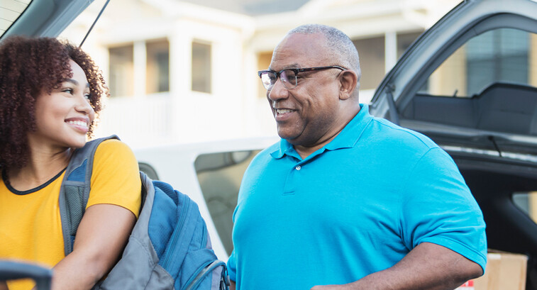 A student and and older adult unload a car during college move-in day