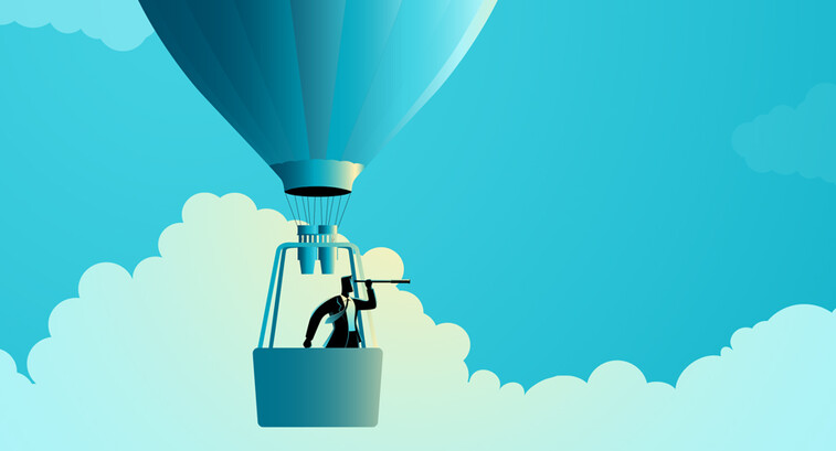 A man in a hot air balloon looks ahead as he soars through the clouds