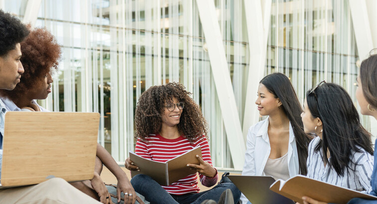 A group of students chat outside on a college campus