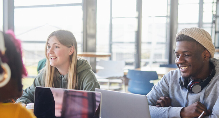 Diverse group of students smiling and studying at computers