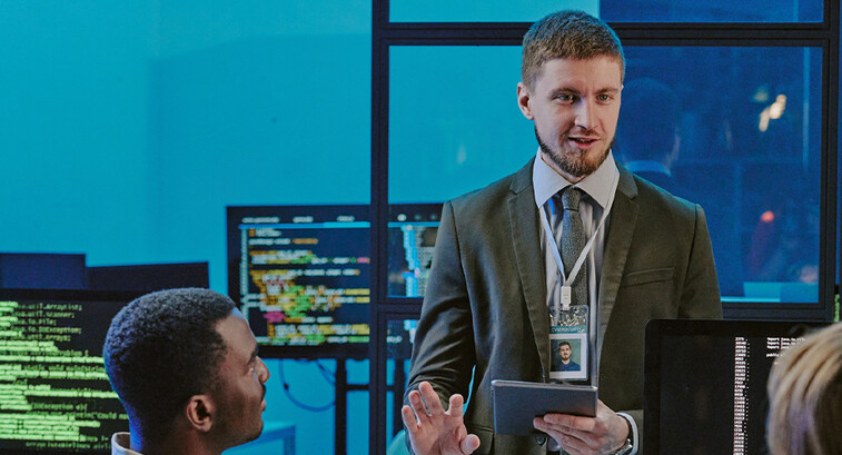 exec talking to 2 people in front of computer screens