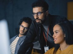 A professor helping some students at a computer screen
