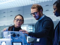 Three people inspect a robotics tool