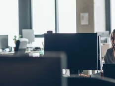 A woman works at a desk in a mostly empty office