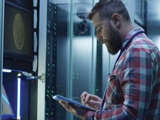 A man works on a tablet inside a large data center