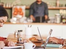 Two students work remotely in a coffee shop