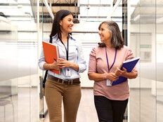 Two women chat about CIEM in an open hallway