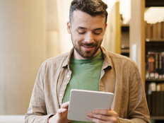 A man looks at a tablet inside a library