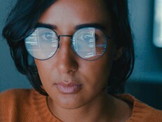 A woman's face with computer code reflected in her glasses