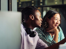 Two people work together at a desktop computer