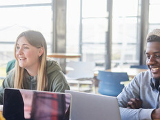 Diverse group of students smiling and studying at computers
