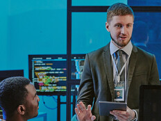 exec talking to 2 people in front of computer screens