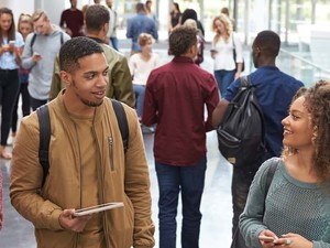 College students walk and talk in a crowded modern building