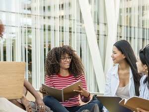 A group of students chat outside on a college campus