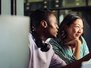 Two people work together at a desktop computer