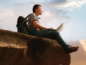Student using laptop in the wilderness
