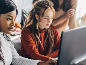 Two students working at computers in a classroom
