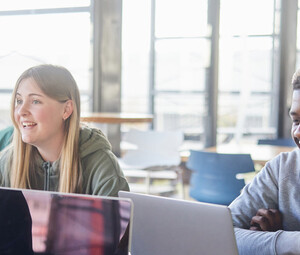 Diverse group of students smiling and studying at computers