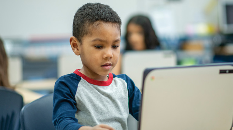 K–12 student using laptop device in classroom for learning
