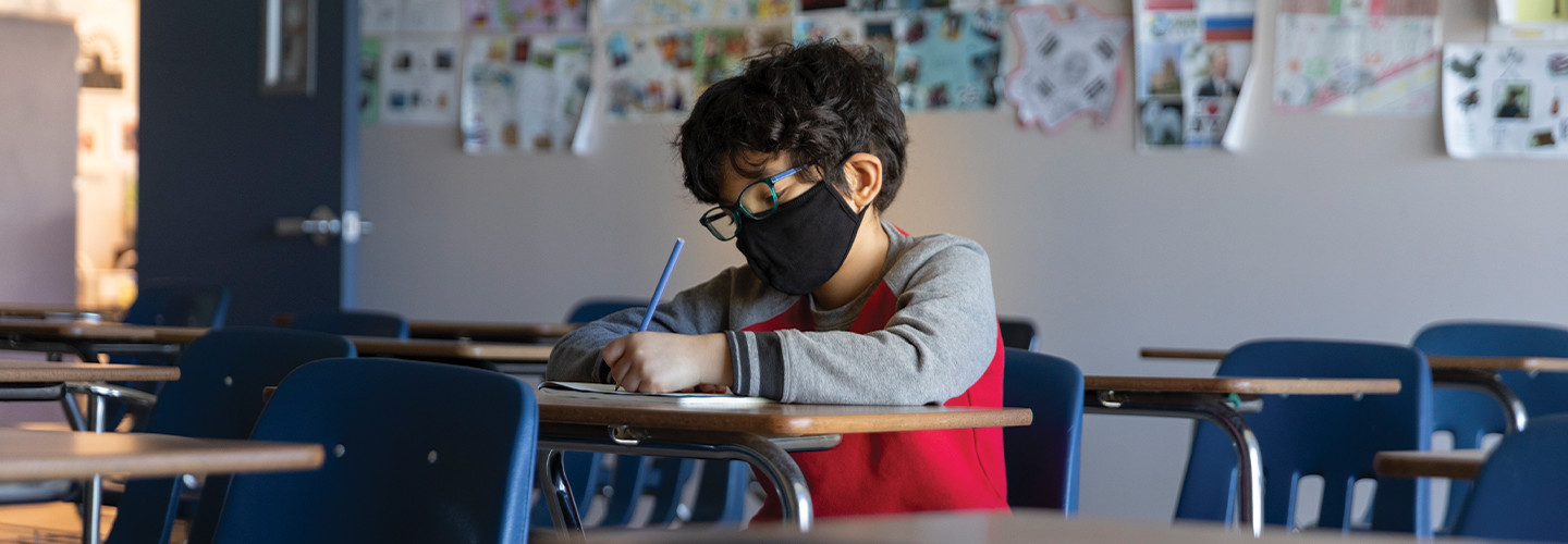 boy with mask in hybrid classroom