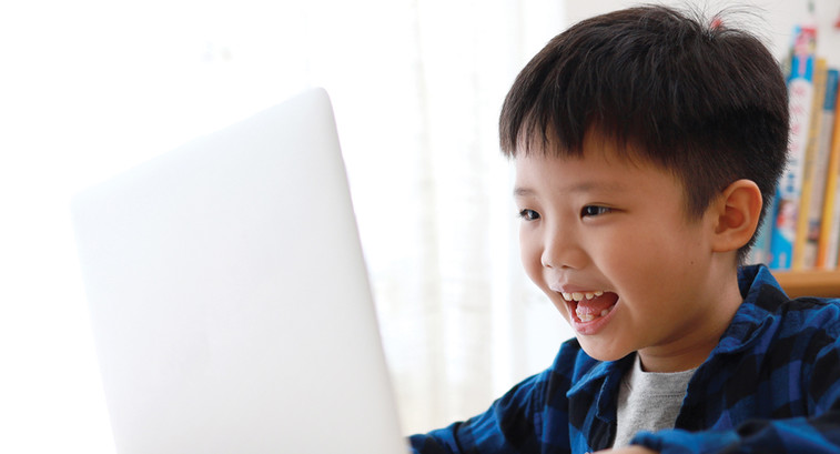 young boy online learning smiling at his computer