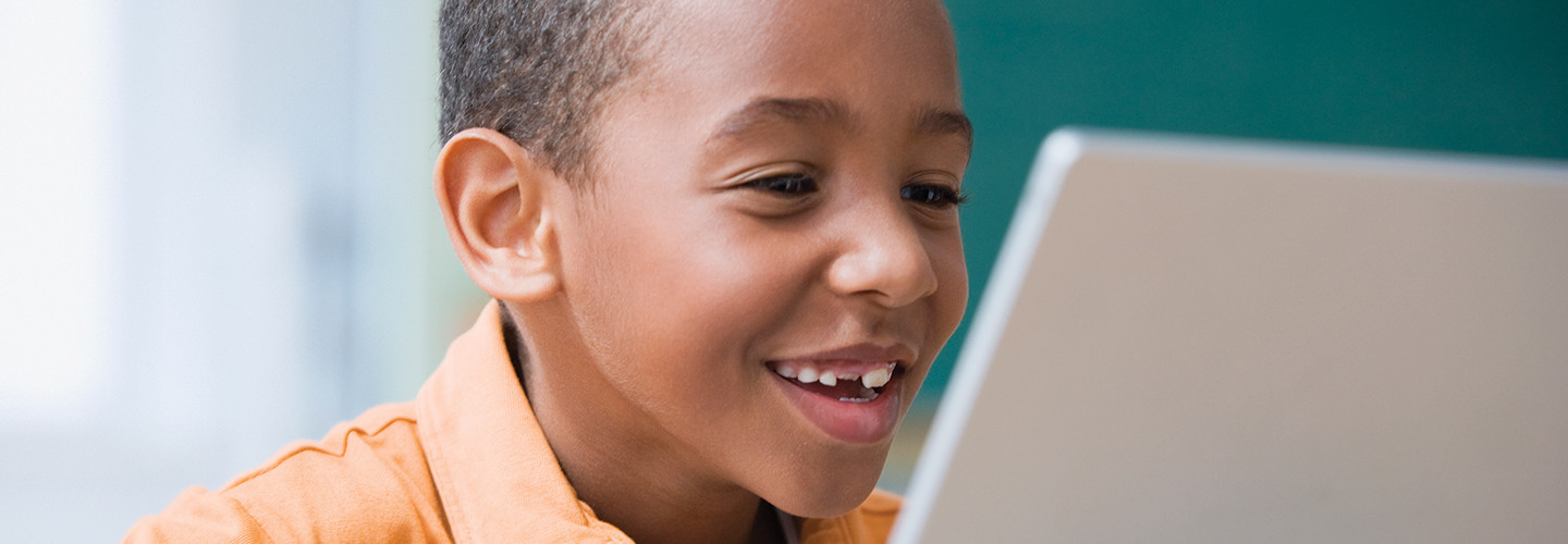 Boy smiling looking at his computer. 