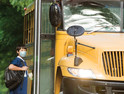 Little boy getting on school bus in a mask