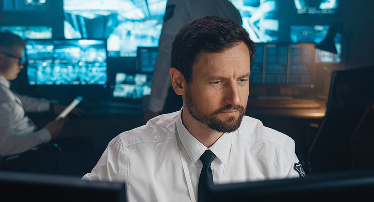 Man studying cyber threats on screen in a room with colleagues