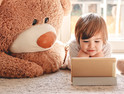 Kindergarten student learns to read on gold tablet with two toy bears