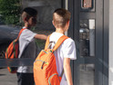 Student entering school door with backpack