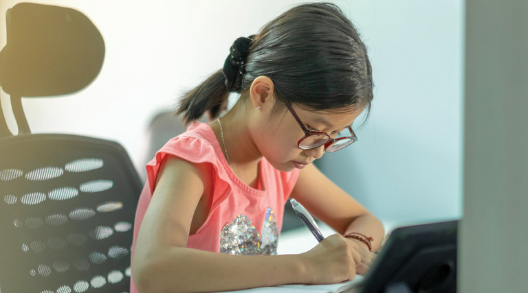 Young girl sitting at desk doing schoolwork