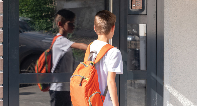 Student entering school door with backpack