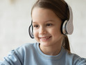 girl with headphones smiling at laptop screen