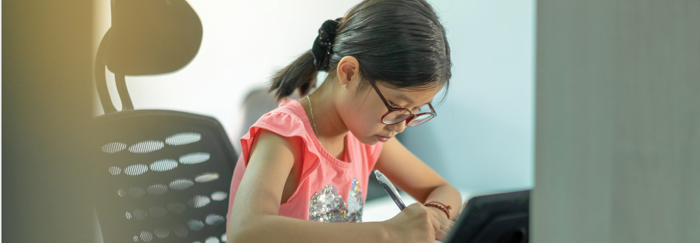 Young girl sitting at desk doing schoolwork