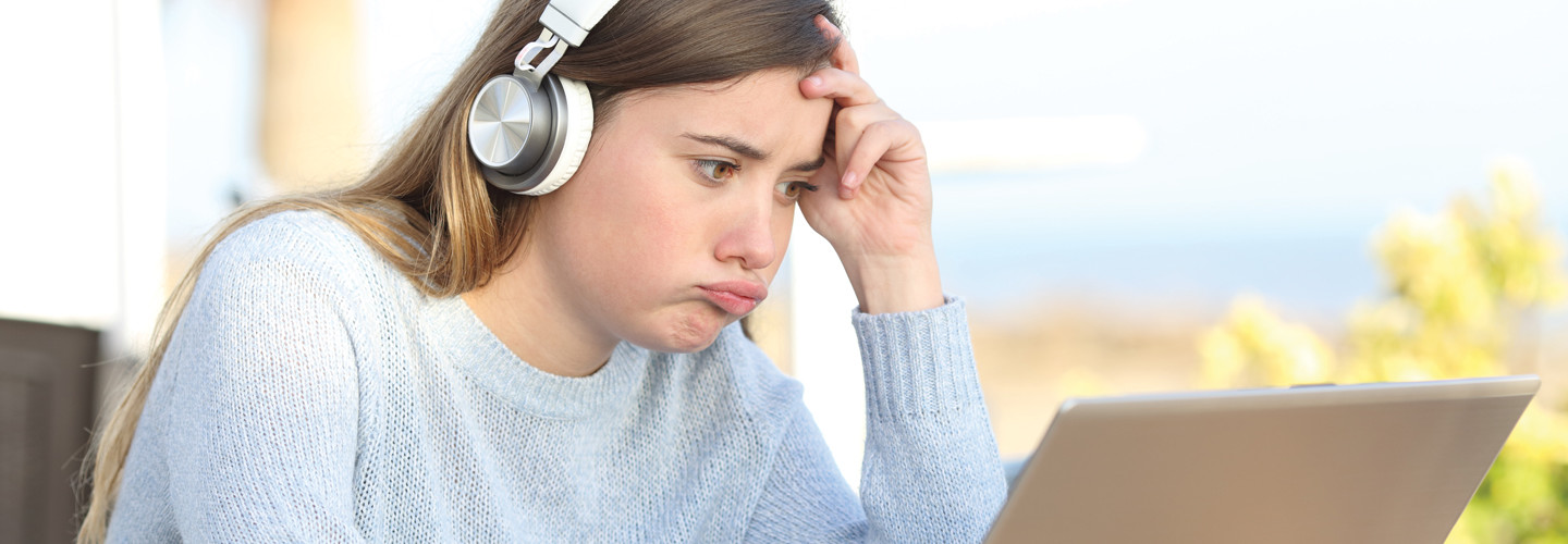 Frustrated student with headphones staring at laptop